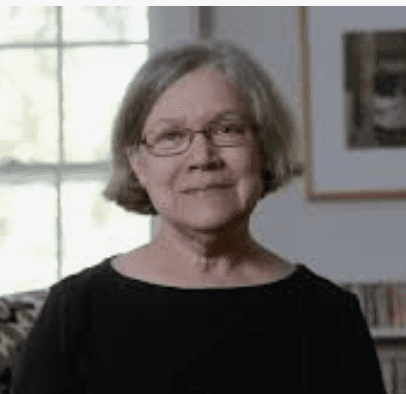 Middle aged white woman swith grey hair styled in a bob with glasses in a casual dark top 